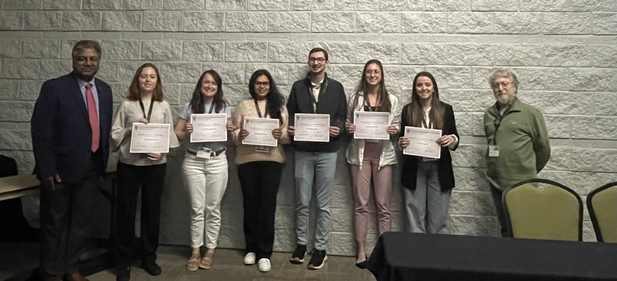 Winners of the 2025 IPBGG spring retreat poster competition pose in a row while holding their award certificates.